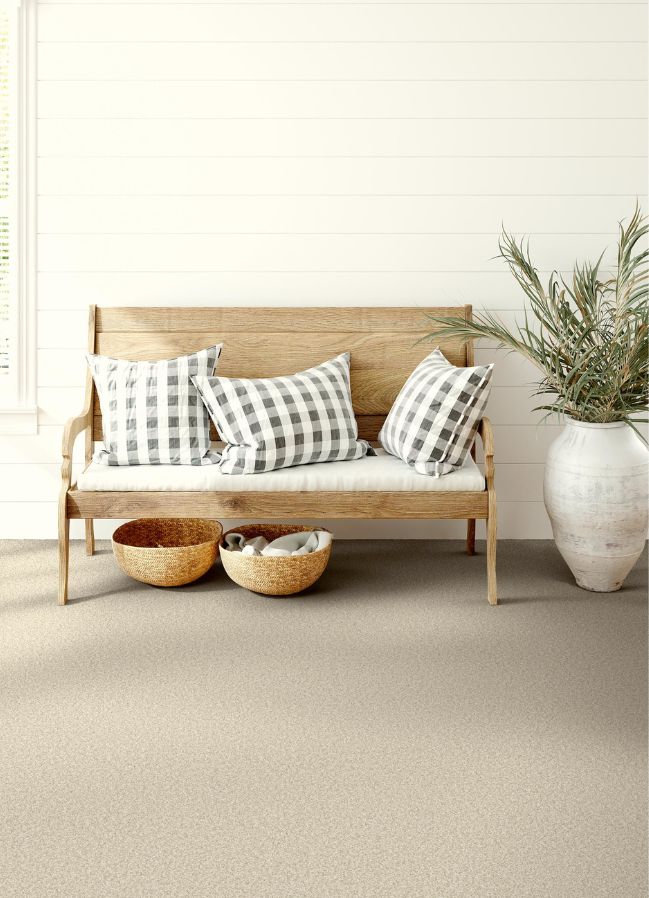 beige carpets in an entryway with a wood bench and plant